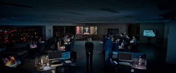 Movie still from “The First Purge” (2018), directed by Gerard McMurray – A group of people in a dark room watching a man on a television screen; Wide shot, High angle