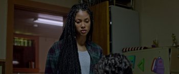 Movie still from “The First Purge” (2018), directed by Gerard McMurray – A young woman with long braids wearing a plaid shirt; Close Up shot, Over the shoulder angle