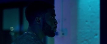 Movie still from “The First Purge” (2018), directed by Gerard McMurray – A person with a beard looking to the side; Close Up shot, Over the shoulder angle