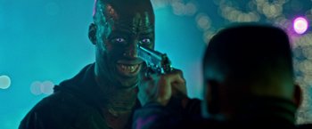 Movie still from “The First Purge” (2018), directed by Gerard McMurray – A man with a green face is holding a knife; Close Up shot, Over the shoulder angle