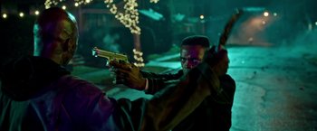 Movie still from “The First Purge” (2018), directed by Gerard McMurray – A man holding a gun while standing next to a tree; Close Up shot, Over the shoulder angle