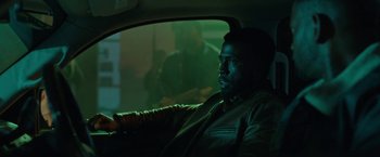 Movie still from “The First Purge” (2018), directed by Gerard McMurray – A man sitting in the back seat of a car at night; Medium shot, Over the shoulder angle