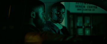 Movie still from “The First Purge” (2018), directed by Gerard McMurray – Two men sitting in the back of a car at night; Close Up shot, Over the shoulder angle