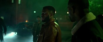 Movie still from “The First Purge” (2018), directed by Gerard McMurray – A man wearing a brown leather jacket standing in the dark; Medium shot, Over the shoulder angle