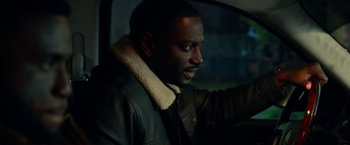 Movie still from “The First Purge” (2018), directed by Gerard McMurray – A man wearing a leather jacket sitting in a car; Close Up shot, Over the shoulder angle