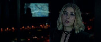 Movie still from “The First Purge” (2018), directed by Gerard McMurray – A woman in a black jacket is standing in front of a tv; Close Up shot, Over the shoulder angle