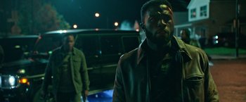 Movie still from “The First Purge” (2018), directed by Gerard McMurray – A man standing next to another man in front of a car; Medium shot, Over the shoulder angle