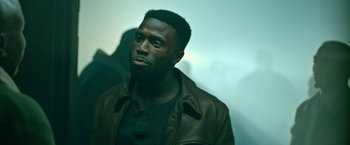 Movie still from “The First Purge” (2018), directed by Gerard McMurray – A man in a brown jacket looking to his left; Close Up shot, Low angle