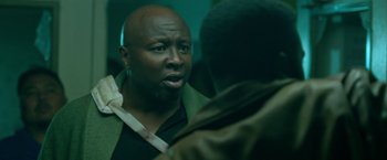 Movie still from “The First Purge” (2018), directed by Gerard McMurray – A man with a beard is talking to another man; Close Up shot, Low angle
