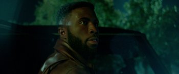Movie still from “The First Purge” (2018), directed by Gerard McMurray – A person with a beard in a car; Close Up shot, Over the shoulder angle