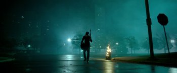 Movie still from “The First Purge” (2018), directed by Gerard McMurray – A man walking down a street holding a guitar; Wide shot, High angle