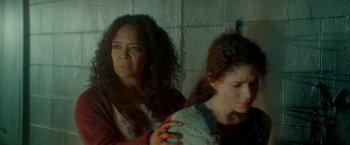 Movie still from “The First Purge” (2018), directed by Gerard McMurray – Two women are looking at each other through a glass window; Medium shot, Over the shoulder angle