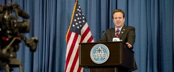 Movie still from “The First Purge” (2018), directed by Gerard McMurray – A man standing at a podium in front of an american flag; Medium shot, Low angle