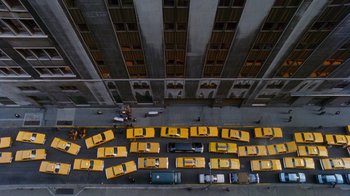Movie still from “The Fisher King” (1991), directed by Terry Gilliam – A bunch of yellow taxis are parked on the side of the road; Extreme Wide shot, Overhead angle