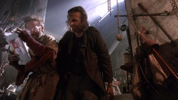 Movie still from “The Fisher King” (1991), directed by Terry Gilliam – A man with a long hair and a beard walking in a building; Medium shot, Low angle