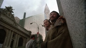 Movie still from “The Fisher King” (1991), directed by Terry Gilliam – Two men standing next to each other in front of a tall building; Medium shot, Low angle