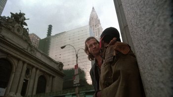 Movie still from “The Fisher King” (1991), directed by Terry Gilliam – A man standing next to another man on the street; Medium shot, Low angle