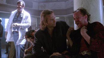 Movie still from “The Fisher King” (1991), directed by Terry Gilliam – A man sitting next to another man in a room; Medium shot, Low angle