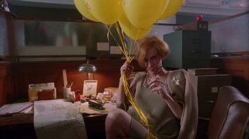 Movie still from “The Fisher King” (1991), directed by Terry Gilliam – A woman sitting in a chair holding a bunch of yellow balloons; Medium shot, Low angle