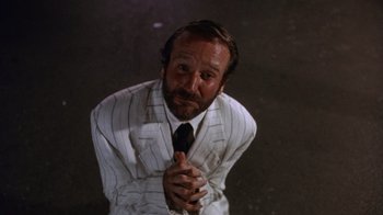 Movie still from “The Fisher King” (1991), directed by Terry Gilliam – A man in a suit and tie praying; Medium shot, Low angle
