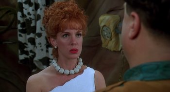Movie still from “The Flintstones” (1994), directed by Brian Levant – A red headed woman wearing a white dress and wearing a necklace; Close Up shot, Over the shoulder angle