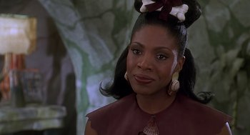 Movie still from “The Flintstones” (1994), directed by Brian Levant – A woman that is wearing a bow on her head; Close Up shot, Over the shoulder angle