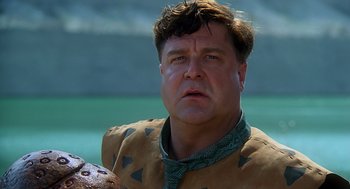 Movie still from “The Flintstones” (1994), directed by Brian Levant – A person wearing a costume near a body of water; Close Up shot, Low angle