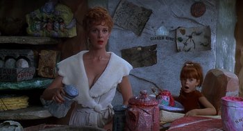 Movie still from “The Flintstones” (1994), directed by Brian Levant – A woman standing in front of a wall with a jar; Medium shot, Over the shoulder angle