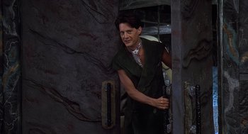 Movie still from “The Flintstones” (1994), directed by Brian Levant – A man standing in front of a stone wall; Medium shot, Over the shoulder angle