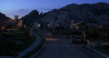 Movie still from “The Flintstones” (1994), directed by Brian Levant – A car driving down a street next to a mountain; Extreme Wide shot, High angle