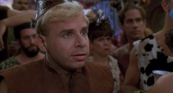 Movie still from “The Flintstones” (1994), directed by Brian Levant – A person wearing a costume; Close Up shot, Over the shoulder angle