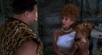 Movie still from “The Flintstones” (1994), directed by Brian Levant – A man and two women talking to each other in front of a stone wall; Medium shot, Over the shoulder angle