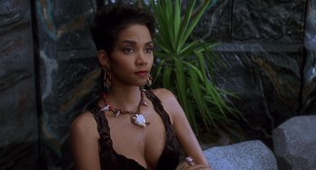 Movie still from “The Flintstones” (1994), directed by Brian Levant – A woman sitting in front of a plant wearing a necklace; Close Up shot, High angle