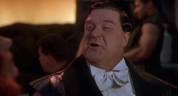 Movie still from “The Flintstones” (1994), directed by Brian Levant – A person wearing a suit and bow tie; Close Up shot, Low angle
