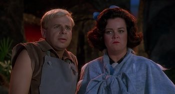 Movie still from “The Flintstones” (1994), directed by Brian Levant – A man and a woman standing next to each other; Close Up shot, Low angle