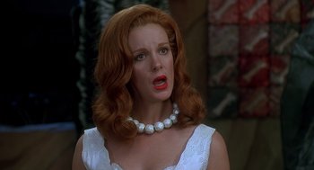 Movie still from “The Flintstones” (1994), directed by Brian Levant – A woman with red hair wearing a white dress and a pearl necklace; Close Up shot, Over the shoulder angle