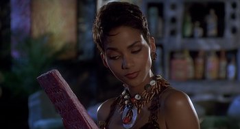 Movie still from “The Flintstones” (1994), directed by Brian Levant – A beautiful woman wearing a necklace holding a book in her hands; Close Up shot, High angle