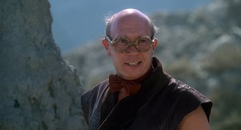 Movie still from “The Flintstones” (1994), directed by Brian Levant – A bald man wearing glasses and a bow tie; Close Up shot, Low angle