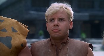 Movie still from “The Flintstones” (1994), directed by Brian Levant – A man with blonde hair is holding something in his hand; Close Up shot, Low angle