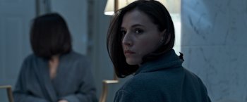 Movie still from “The Foreigner” (2017), directed by Martin Campbell – A young woman with dark brown hair looking at the camera; Close Up shot, Over the shoulder angle