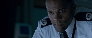 Movie still from “The Foreigner” (2017), directed by Martin Campbell – A person wearing a uniform; Close Up shot, Over the shoulder angle
