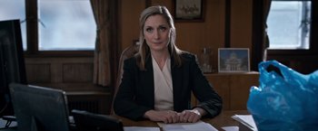 Movie still from “The Foreigner” (2017), directed by Martin Campbell – A woman sitting at a table with papers; Medium shot, Low angle