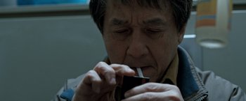 Movie still from “The Foreigner” (2017), directed by Martin Campbell – An older man smoking a cigarette while holding a cell phone in his hand; Close Up shot, High angle