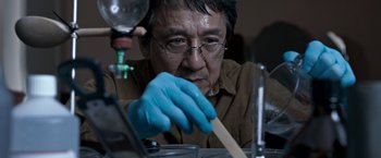 Movie still from “The Foreigner” (2017), directed by Martin Campbell – A man wearing a blue glove and holding a wooden stick; Close Up shot, Low angle