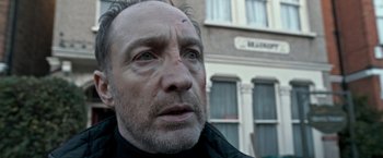 Movie still from “The Foreigner” (2017), directed by Martin Campbell – A person looking at the camera; Close Up shot, Low angle