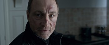 Movie still from “The Foreigner” (2017), directed by Martin Campbell – A person wearing a black jacket; Close Up shot, Low angle