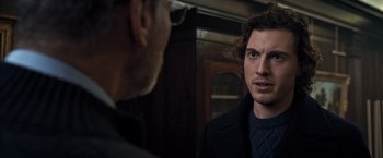 Movie still from “The Foreigner” (2017), directed by Martin Campbell – A man in a black jacket is talking to another man; Close Up shot, Over the shoulder angle