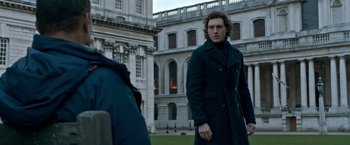 Movie still from “The Foreigner” (2017), directed by Martin Campbell – A man standing in front of an old building; Medium shot, Low angle