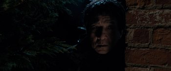 Movie still from “The Foreigner” (2017), directed by Martin Campbell – A man in a dark forest looking at the camera; Close Up shot, Low angle