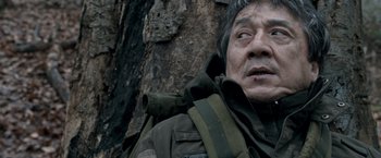 Movie still from “The Foreigner” (2017), directed by Martin Campbell – An older man wearing a jacket and a backpack near a tree; Close Up shot, High angle